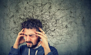 Man som håller händerna i tinningarna och ser förtvivlad och runt huvudet är det en massa krumelurer som gestaltar tankar